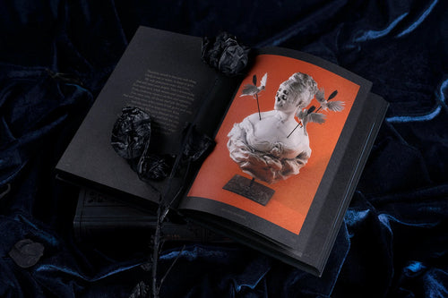 Angled display of the book with an orange illustrated endpaper — Dark Inspiration: 20th Anniversary Edition - Grotesque Illustrations, Art & Design.